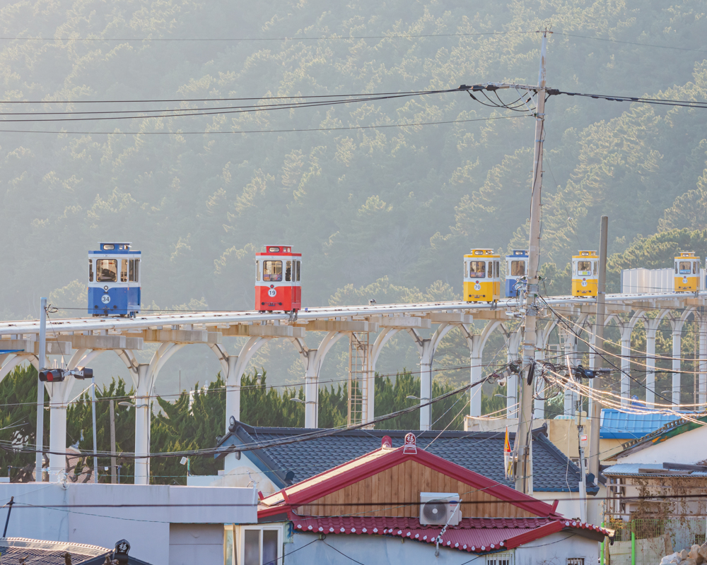 Colourful capsule-style rail cars of the Haeundae Beach Sky Capsule in Busan, South Korea, gliding along the coast.