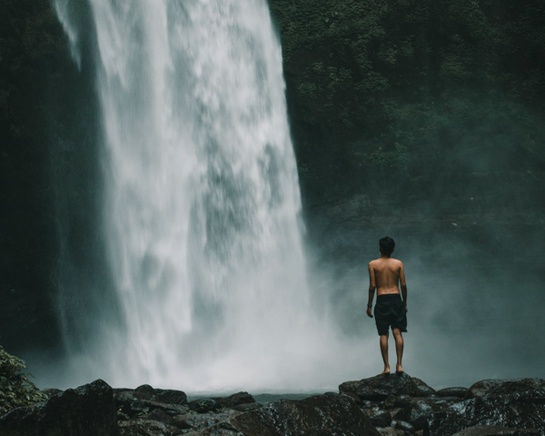 Man standing in front of waterfall in Indonesia