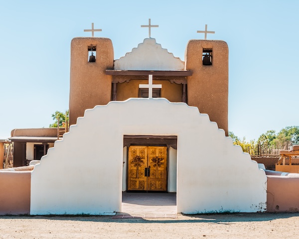 A church in Taos, New Mexico, with a cross adorning the front door, representing its spiritual significance.