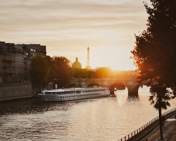 A sunset view of the Seine River in Paris, with a boat peacefully floating on the water's surface.