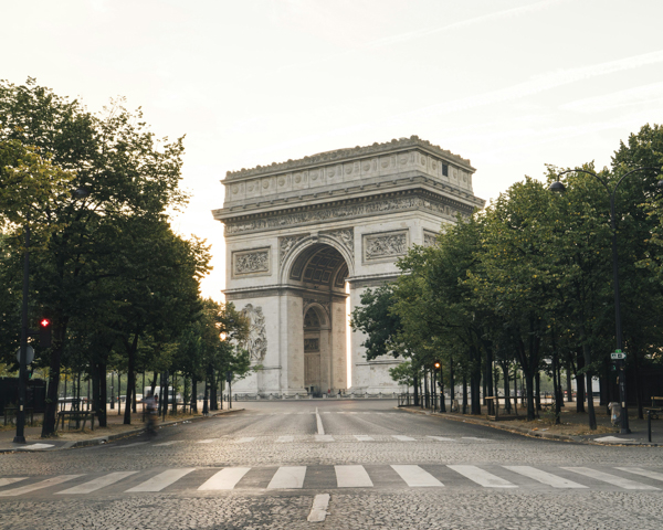 The iconic Arc de Triomphe in Paris, a symbol of history and culture, framed by the lively Parisian streets.