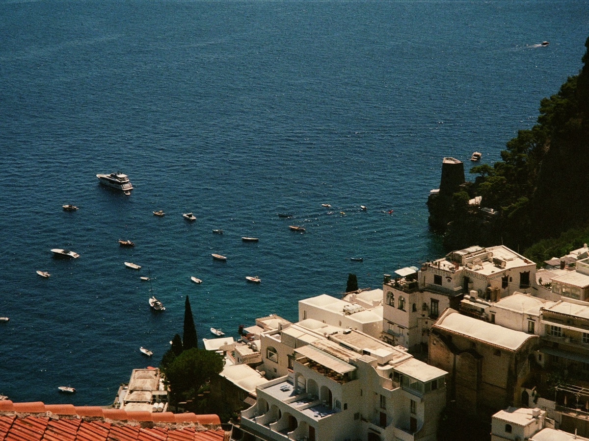 The dramatic cliffs of the Amalfi Coast, Italy, rising from the turquoise sea, with charming villages perched on the cliffside and lush greenery cascading down the slopes.