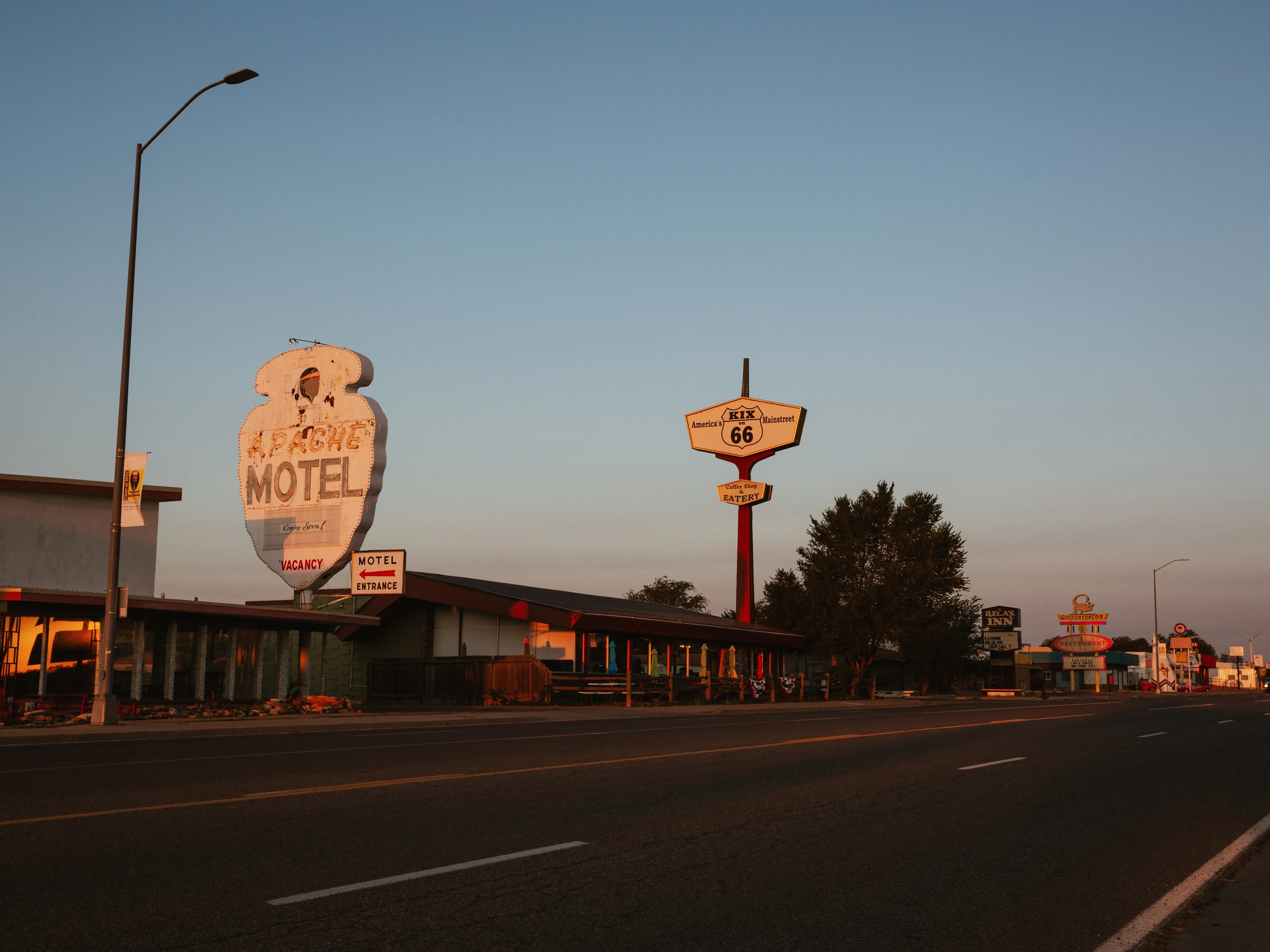 Vintage Route 66 motel signs along a quiet American roadside at sunset under a clear sky.