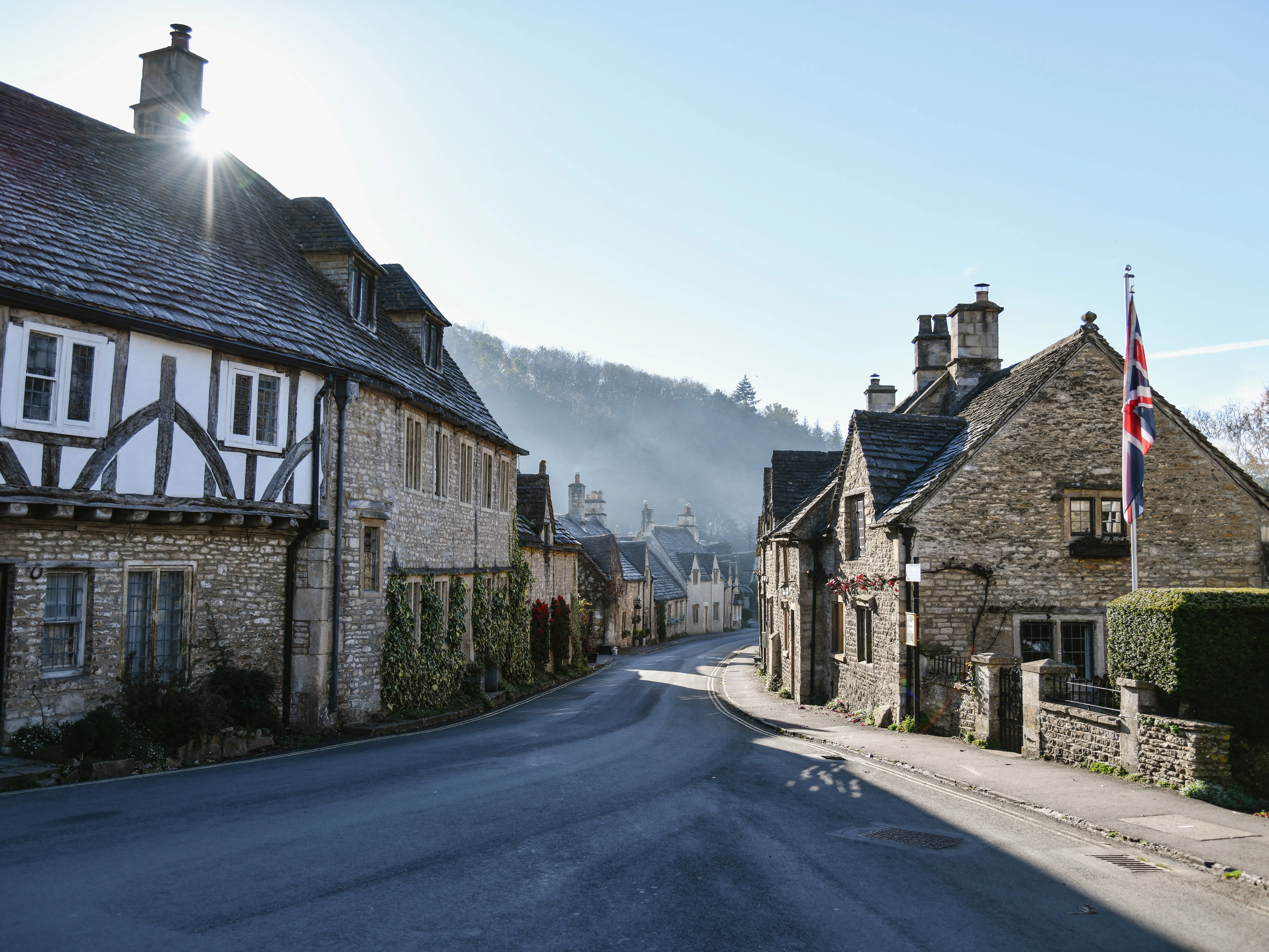 Traditional Cotswolds village street with historic stone houses and a quiet country road, a classic day trip from London.