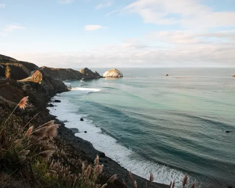 Scenic view of Big Sur Coast in California, showcasing rugged cliffs and the Pacific Ocean under a clear blue sky.