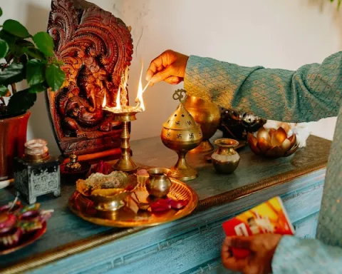 A man lights a candle on a festive table adorned with Diwali decorations and other celebratory items.